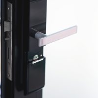 Modern glass and metallic dark front door with chrome handle and digital lock from inside, copy space