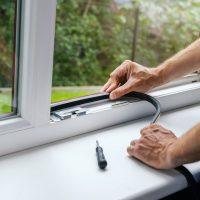 worker installing sealing tape on plastic window frame. banner with copy space