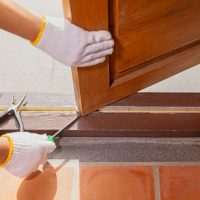 Handyman fixing roller stuck in buttom track of folding door.